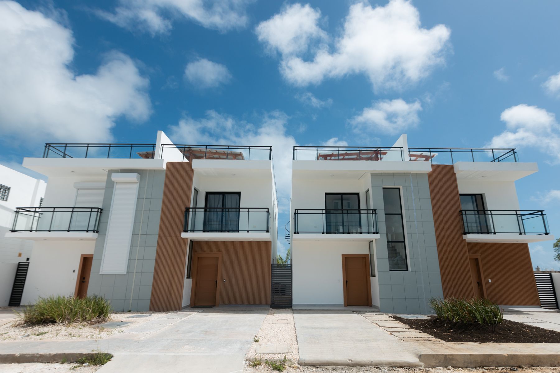 Townhouses de dos niveles con balcones de vidrio y fachada en madera