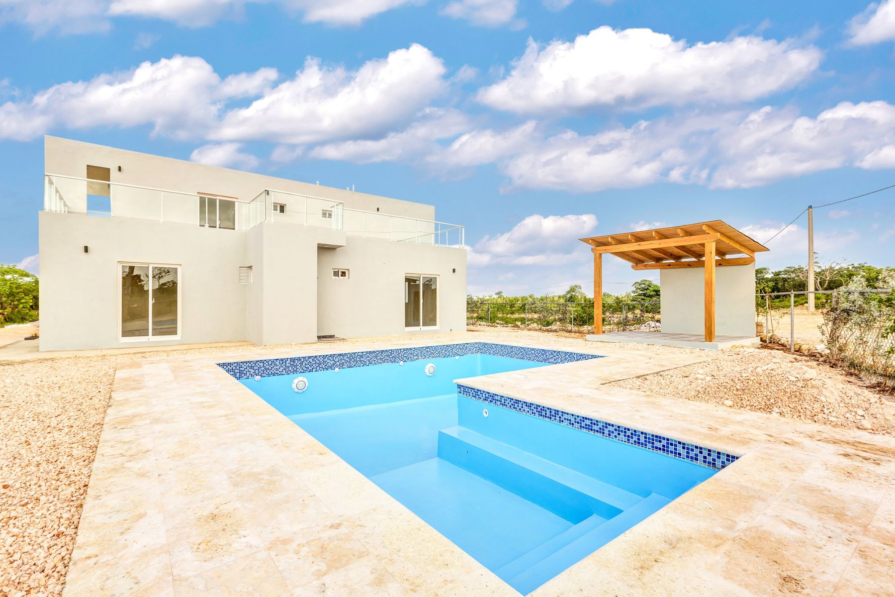 Villa blanca con piscina en L y pérgola de madera